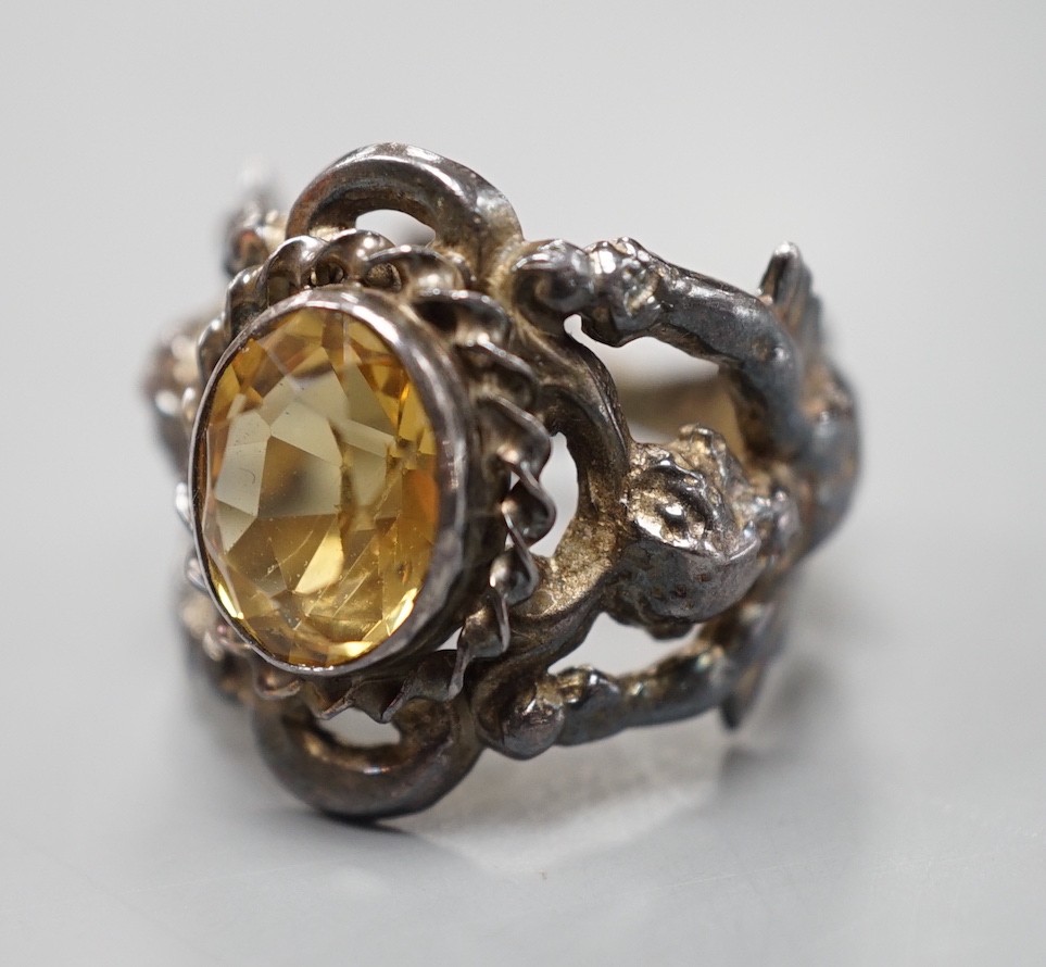 A 1960's silver and oval cut citrine set ring, the shank modelled and twin cupids, size O, gross weight 9.2 grams.